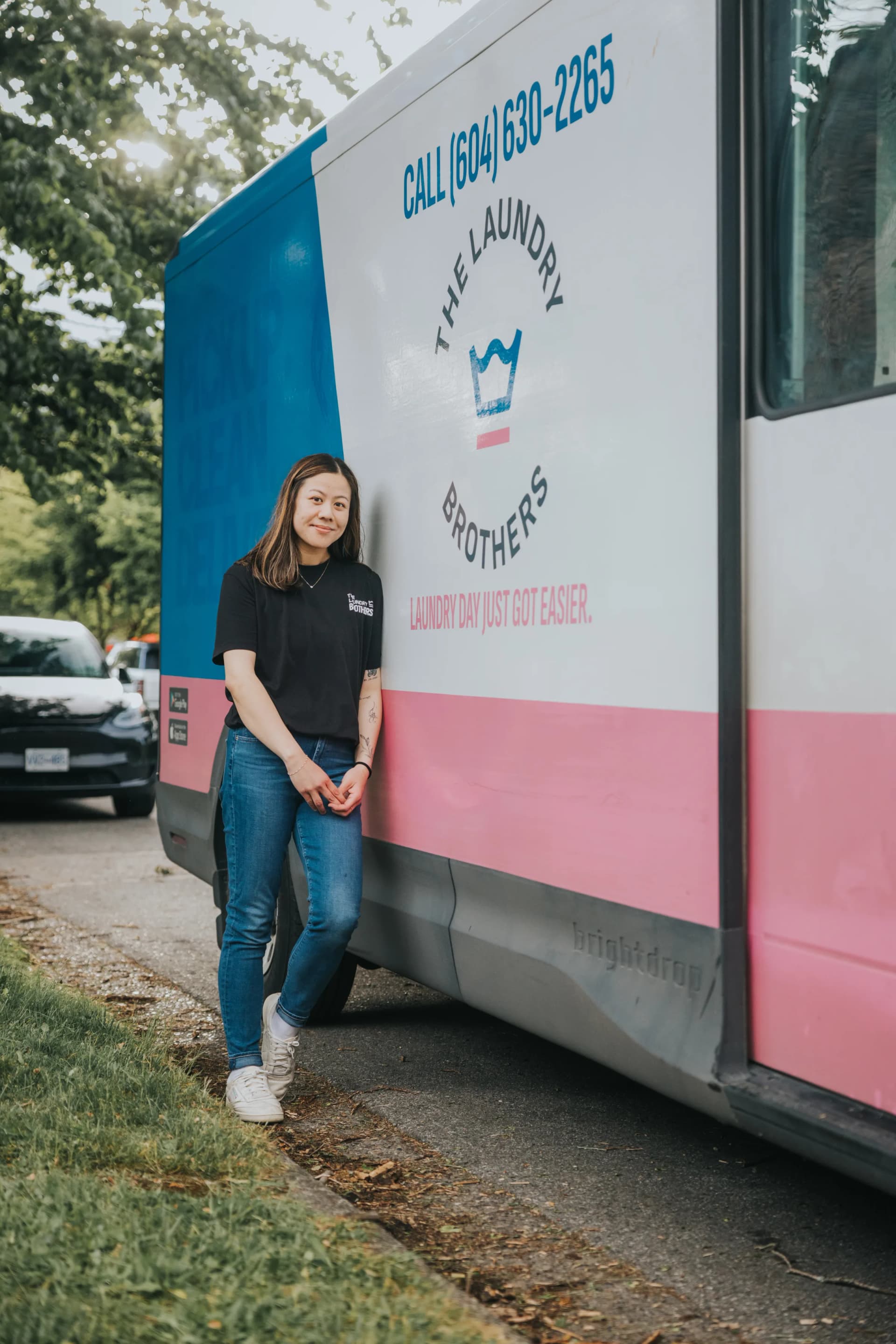 A Laundry Brothers driver standing next to the branded pink and blue delivery van.